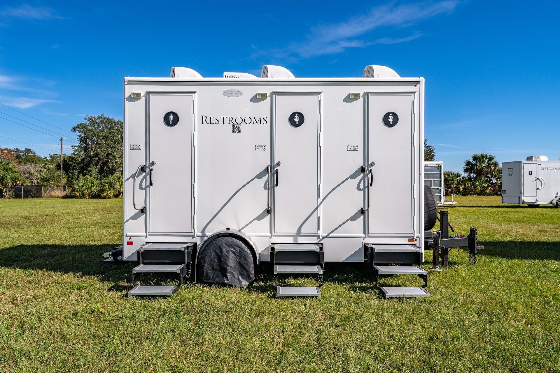 A white trailer is parked in a grassy field
