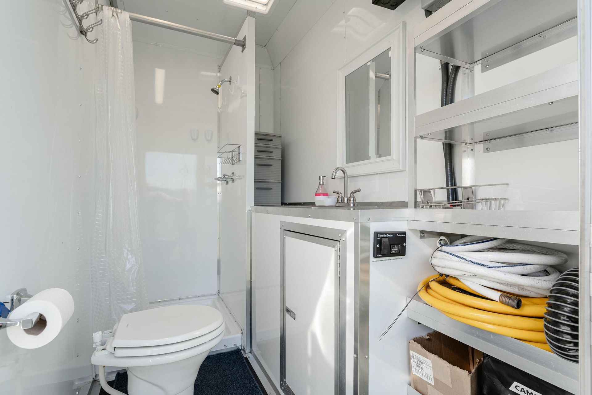 A bathroom with a toilet, sink, mirror, and shower