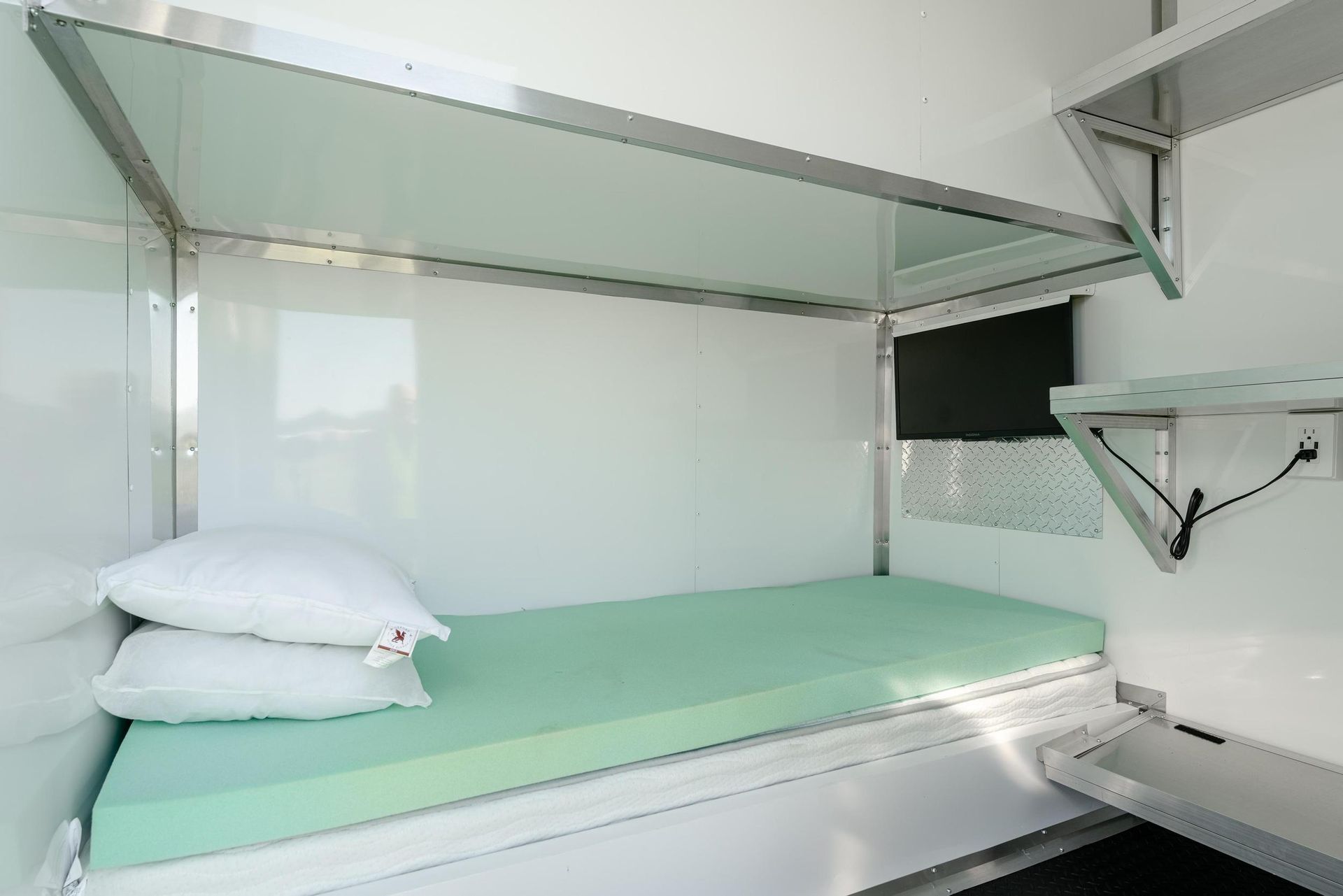 A bunk bed with a green mattress and two pillows in a room