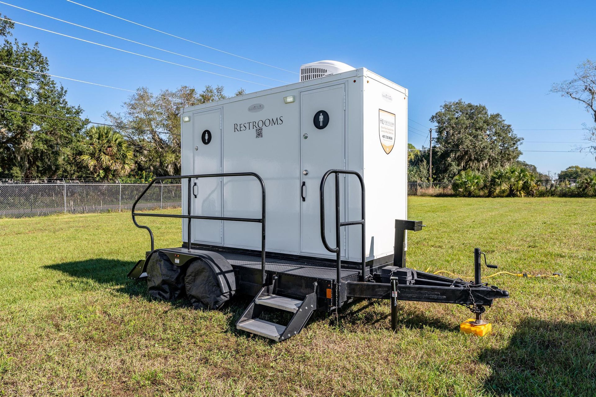 A white trailer is parked in a grassy field