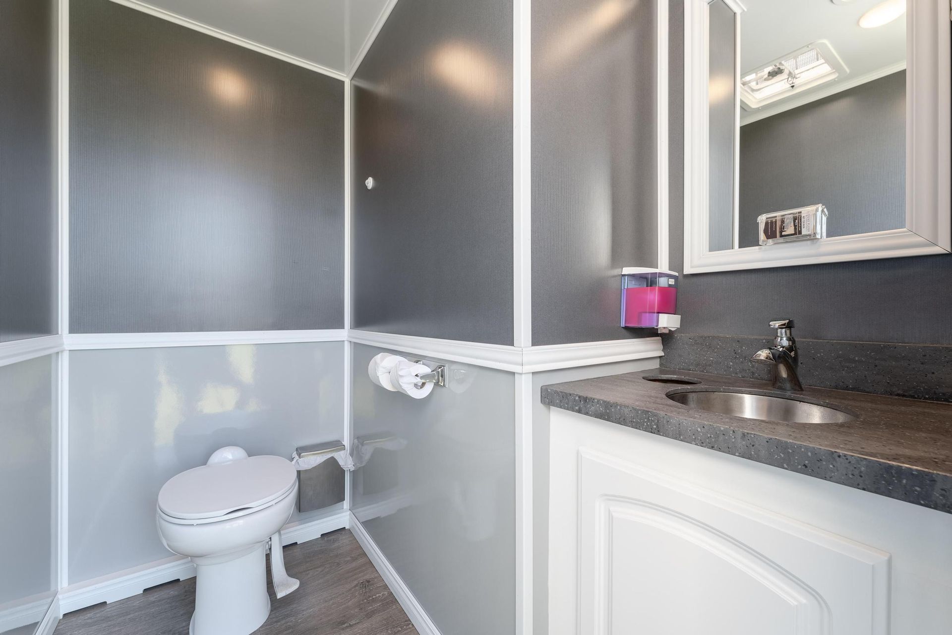 A bathroom with a toilet, sink, and mirror