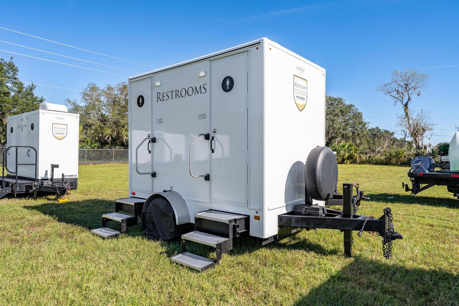 Two white trailers are parked in a grassy field