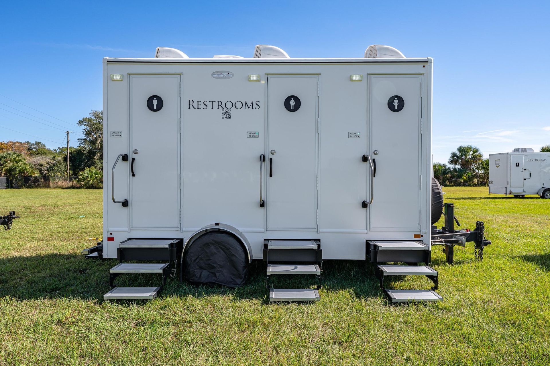 A white trailer is parked in a grassy field