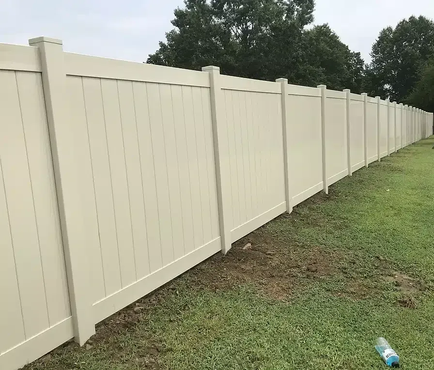 Beige vinyl privacy fence along a grassy yard.