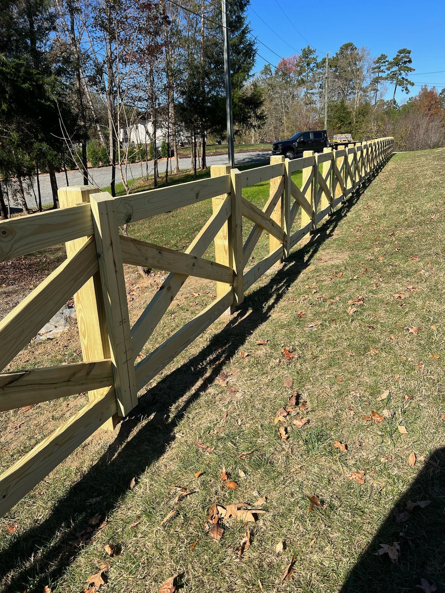Wooden fence with diagonal accents in a grassy yard on a sunny day.