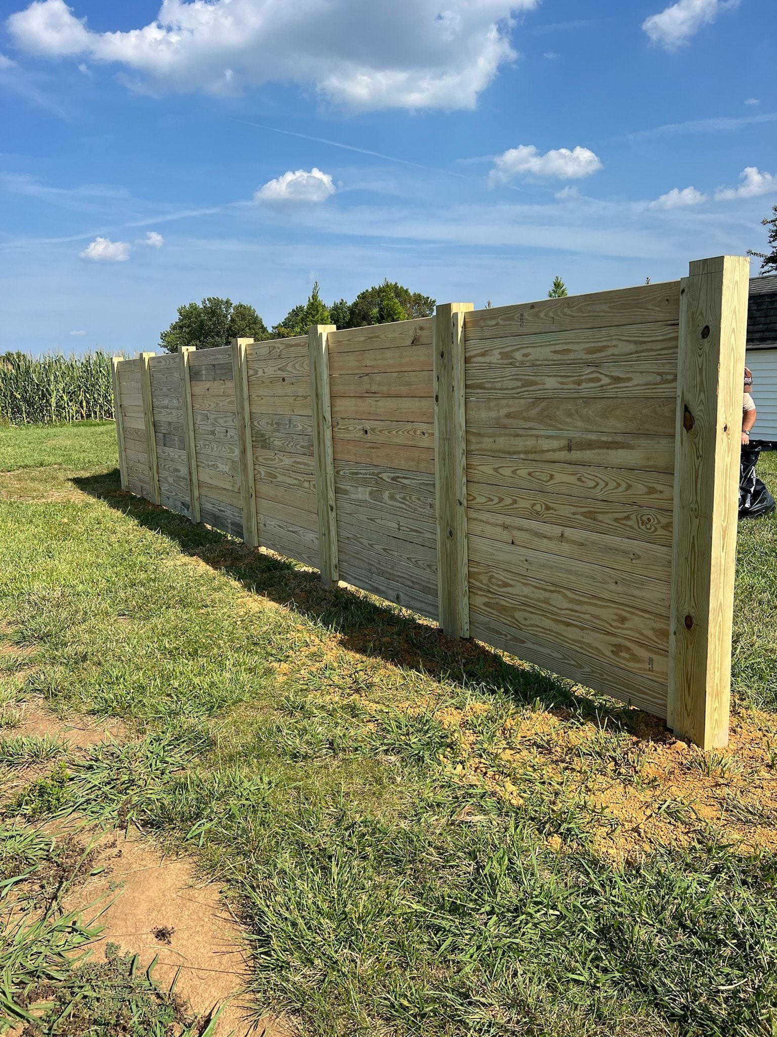 Wooden fence in a grassy field under a blue sky.
