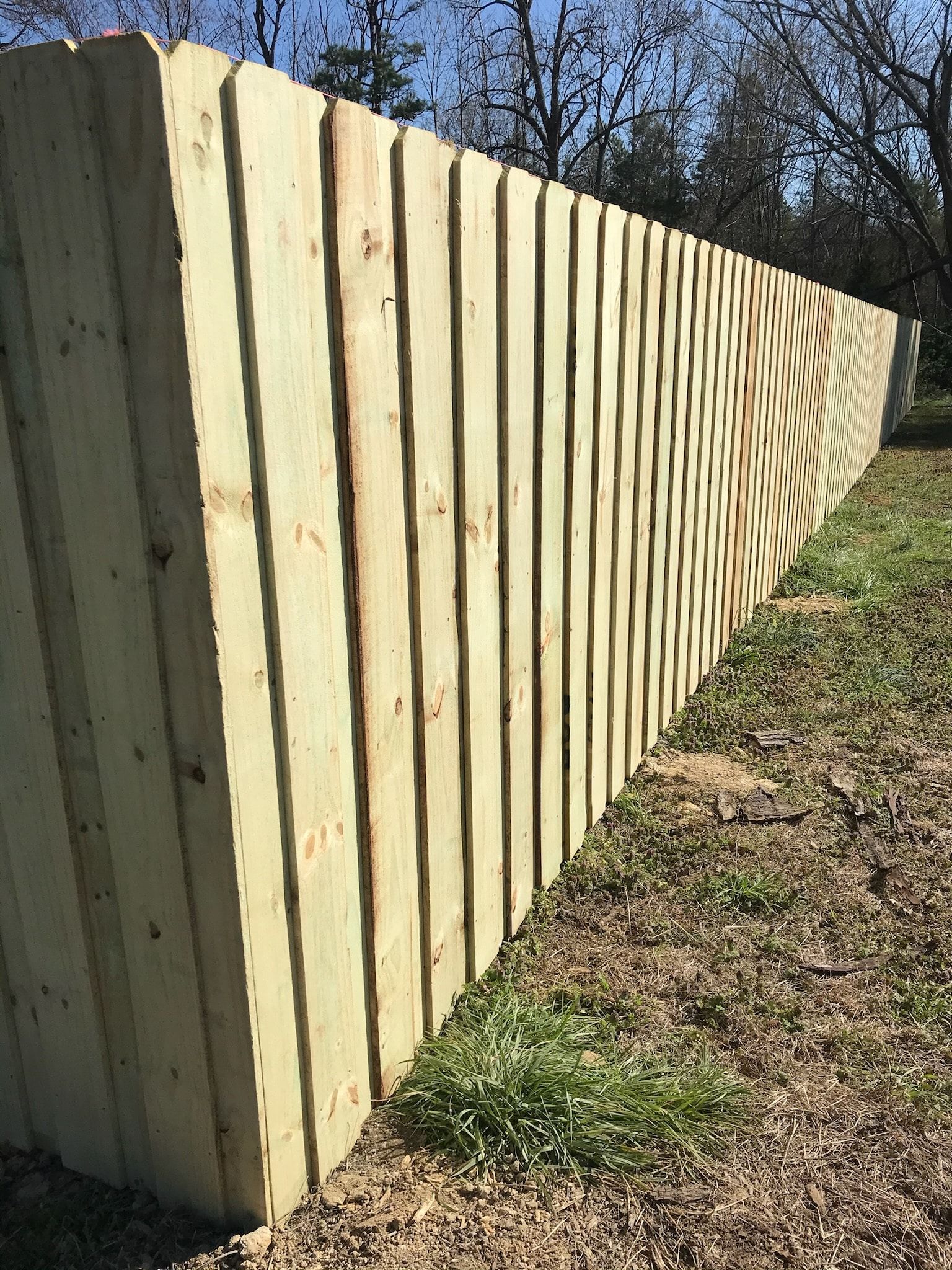 Wooden fence on a slight incline, vertical boards, outdoor setting.