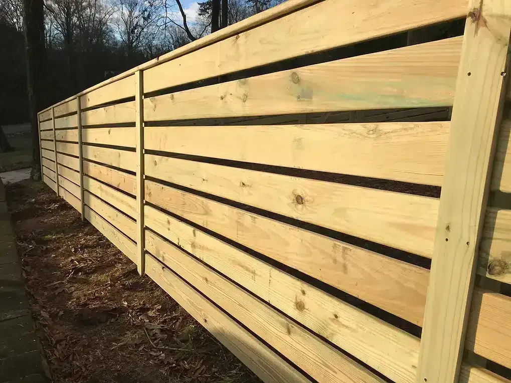 Wooden horizontal slat fence in a yard.