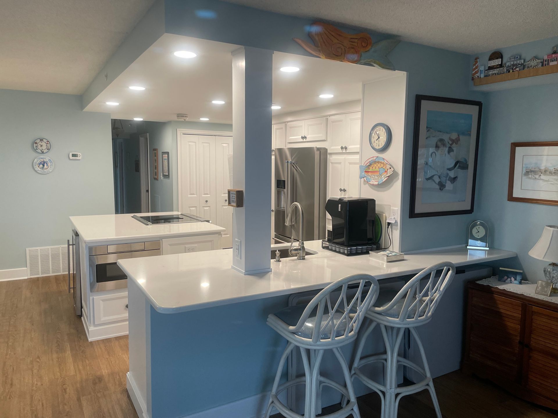 A kitchen with a bar and stools and a refrigerator.