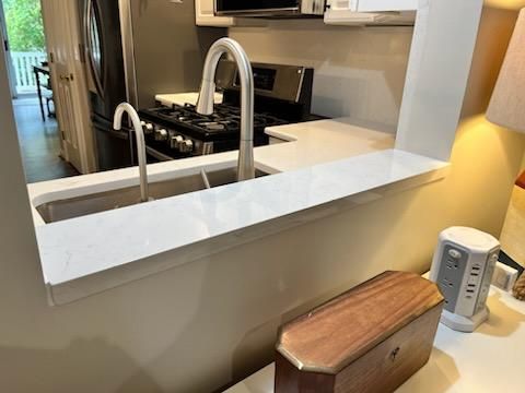 A kitchen sink area with a white countertop and two faucets.