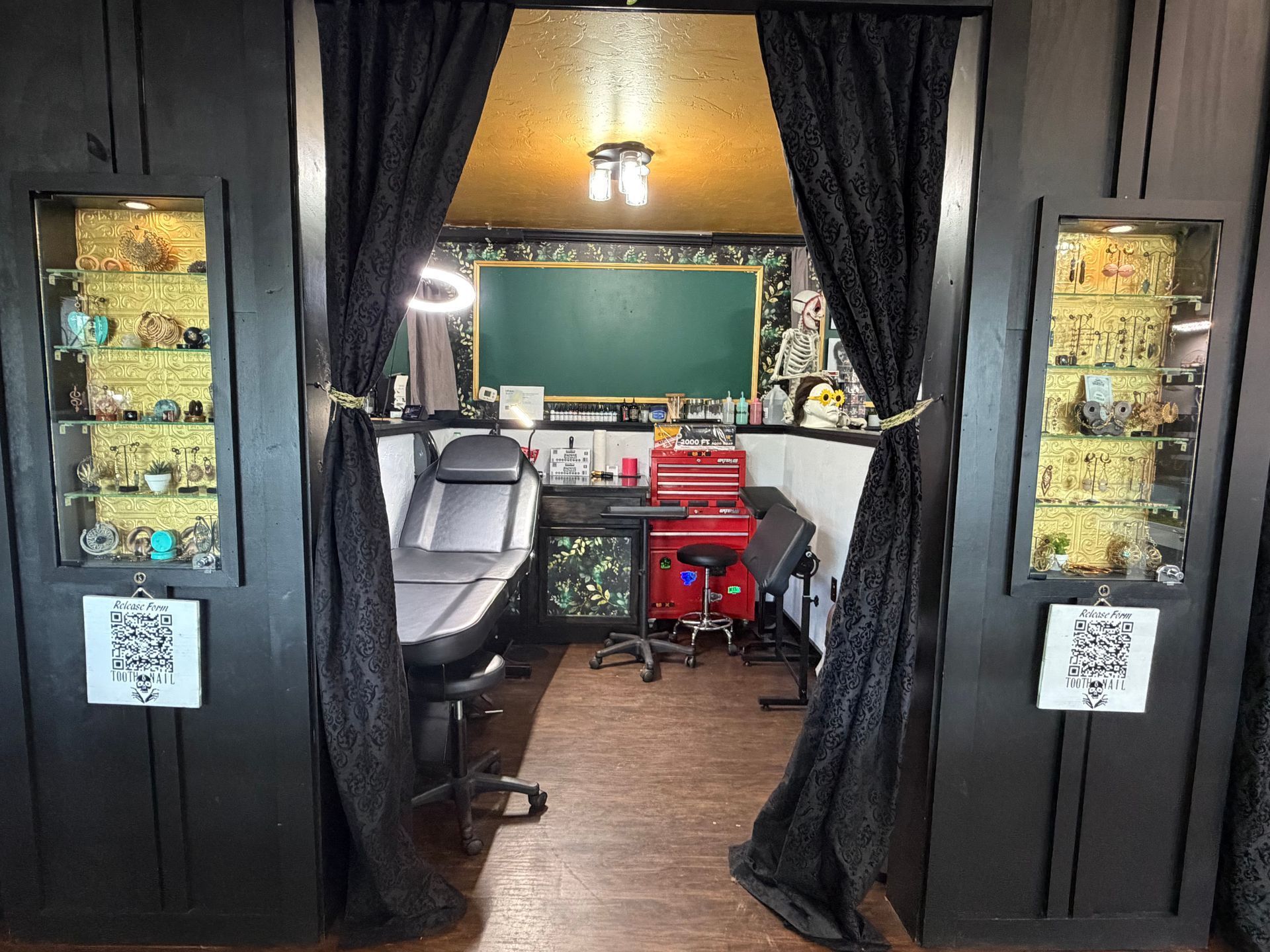 Salon entrance with black curtains framing a stylist chair, red tool cart, and mirrors inside.