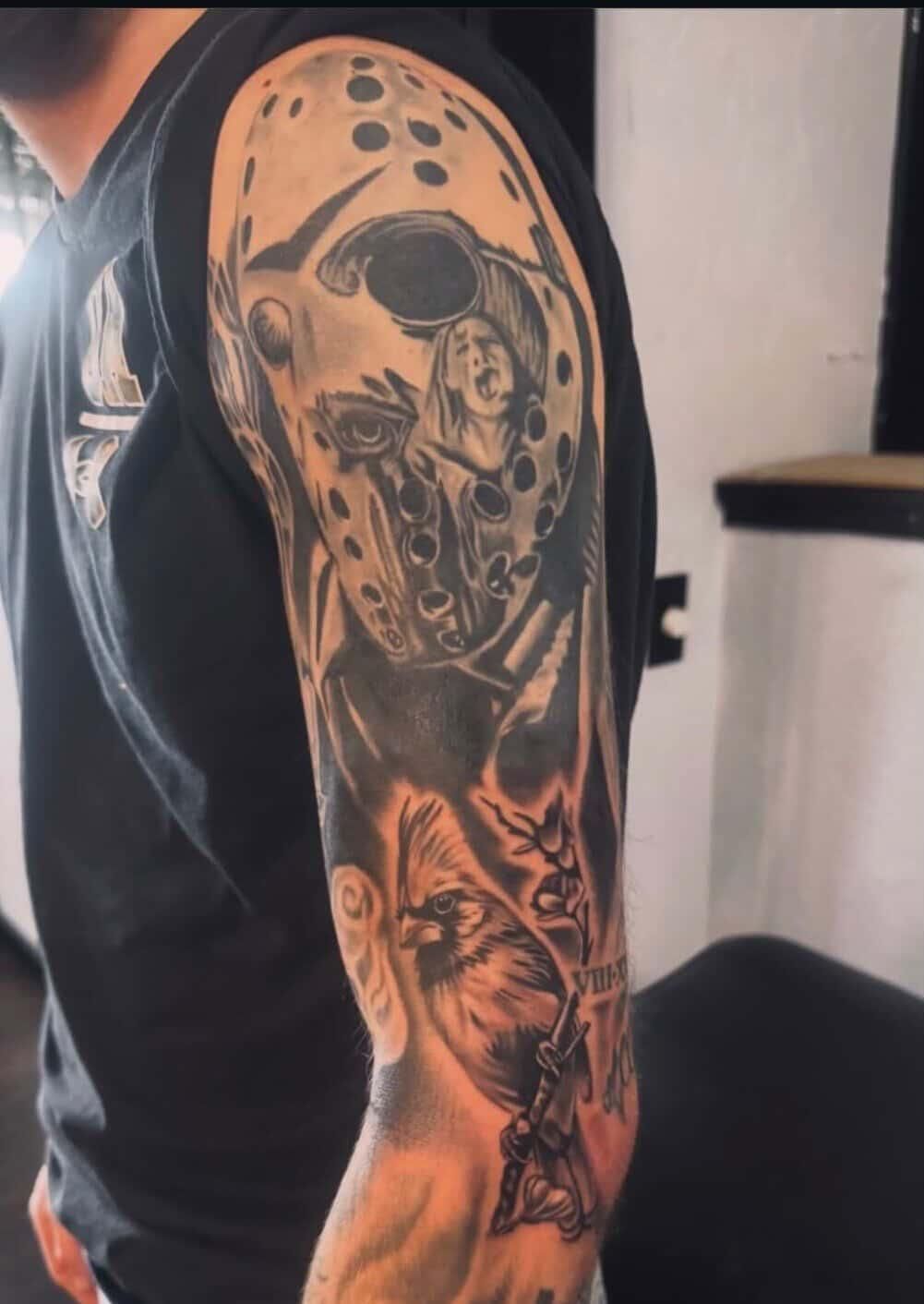 Arm tattoo sleeve with skull and floral designs on a person's upper arm, in black and gray ink