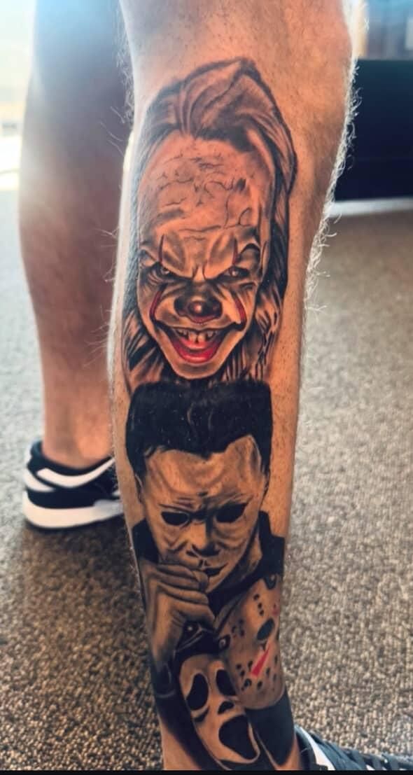 Close-up of a black-and-gray leg tattoo with stacked horror faces on a person’s calf.