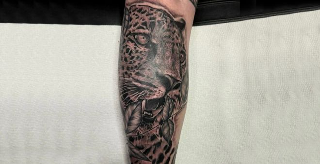 Black-and-gray sleeve tattoo on a forearm.