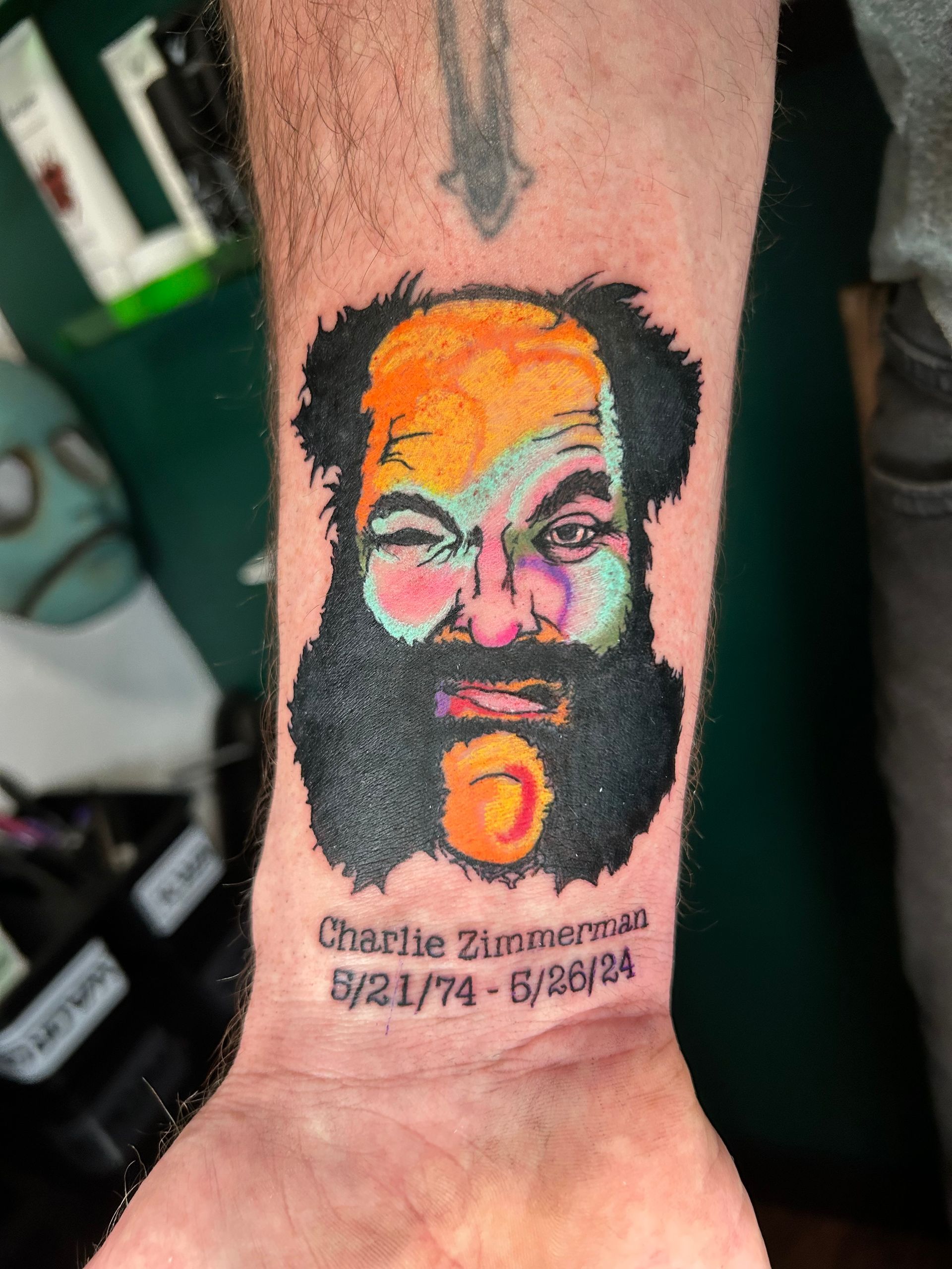 Forearm tattoo portrait of Charlie Manson with date text beneath it