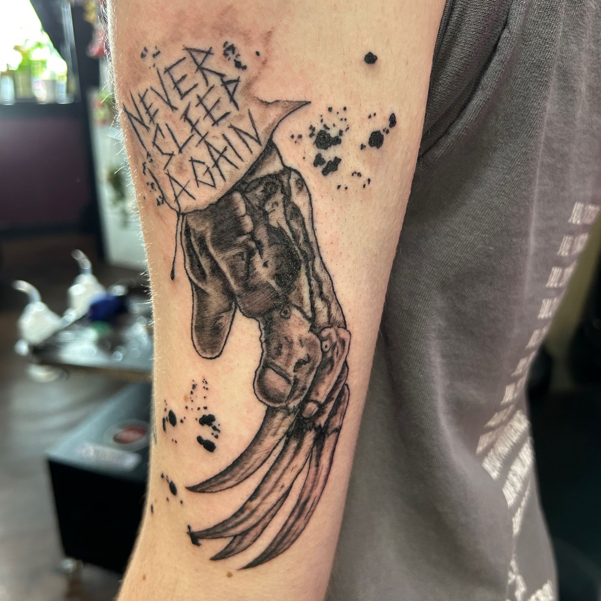 Forearm tattoo of a hand with long claws and the text “NEVER LET ME DOWN” above it