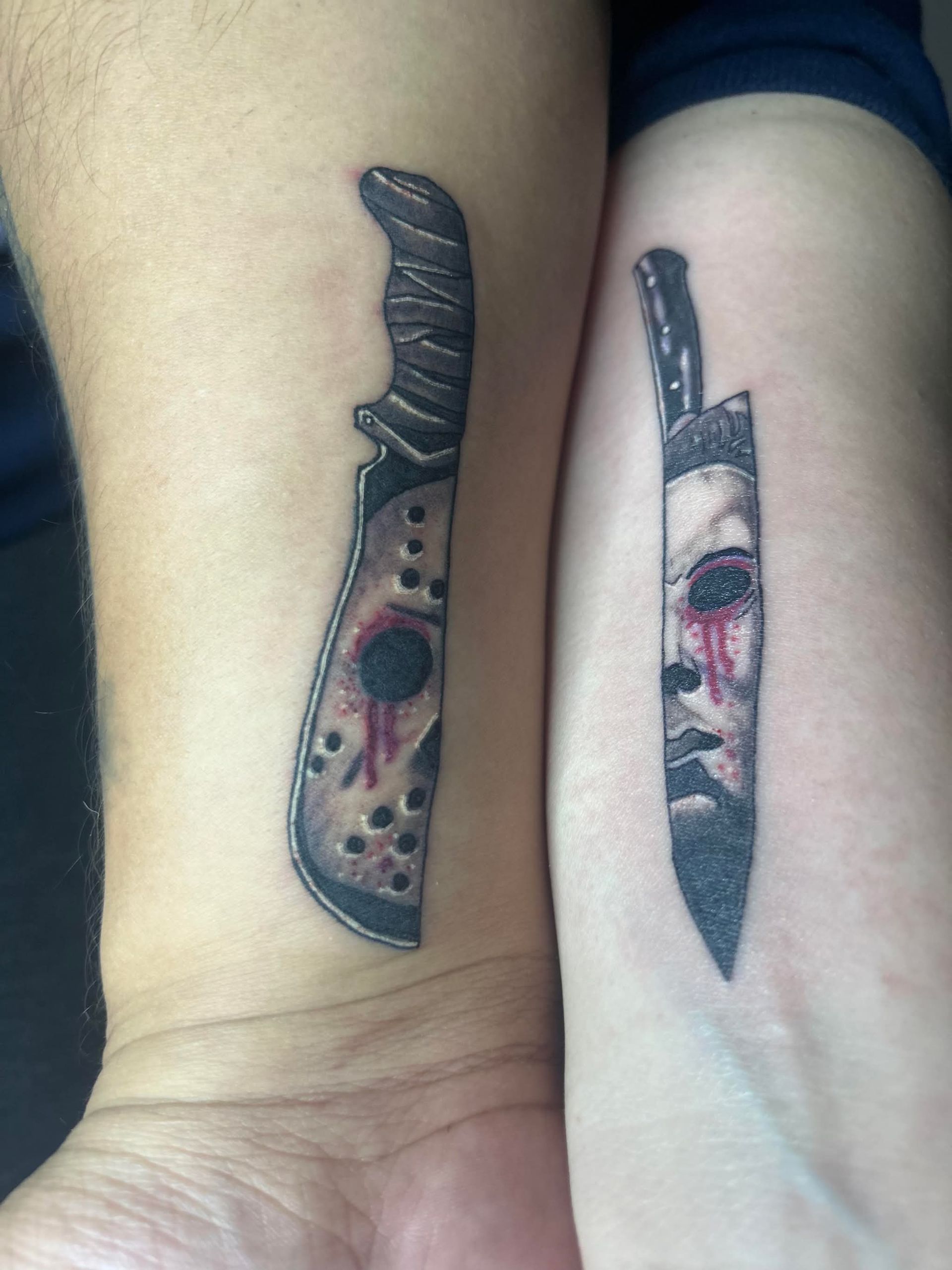 Two matching forearm tattoos of knives with abstract faces and red accents on skin