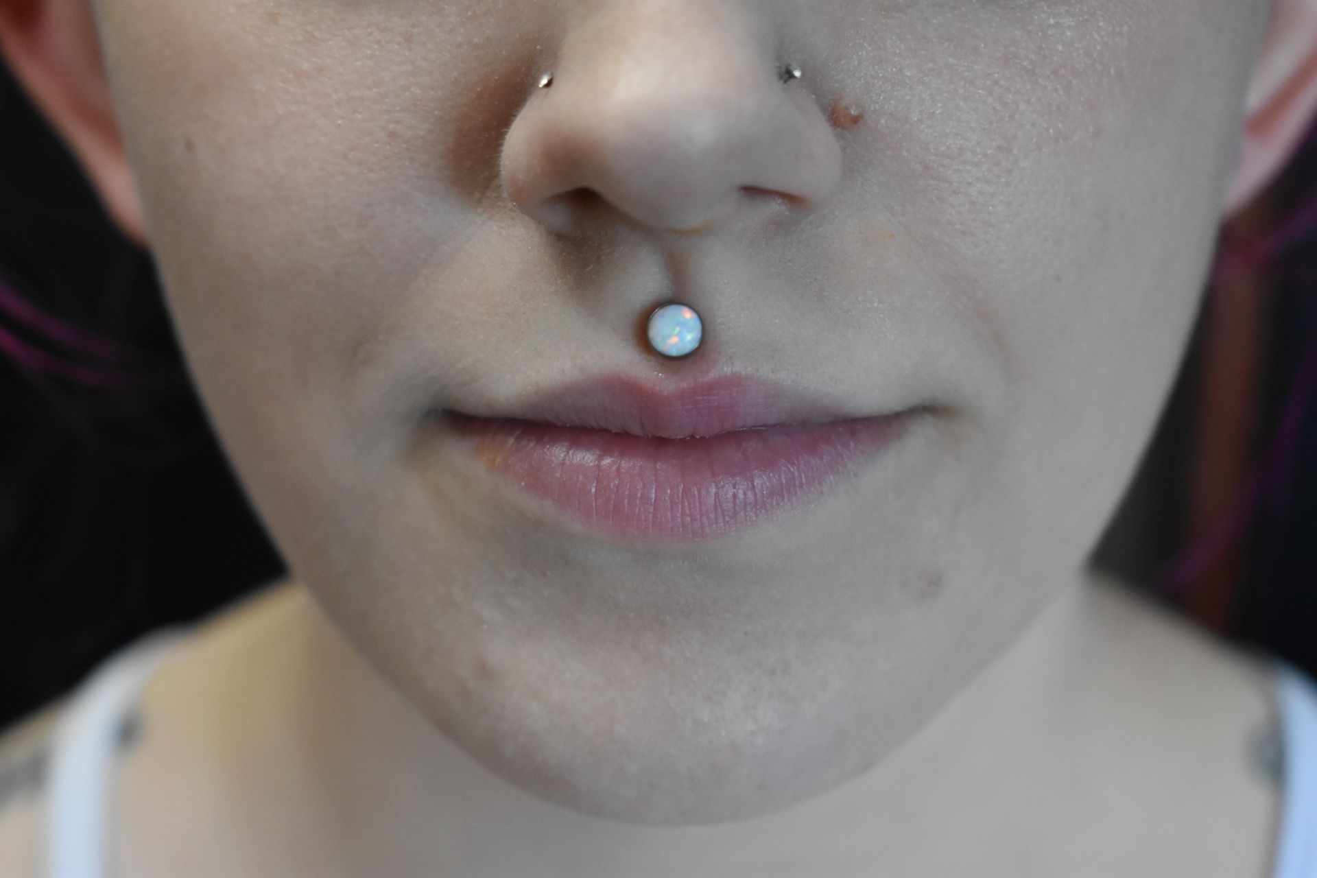 Close-up of a face with a silver nose stud and neutral expression