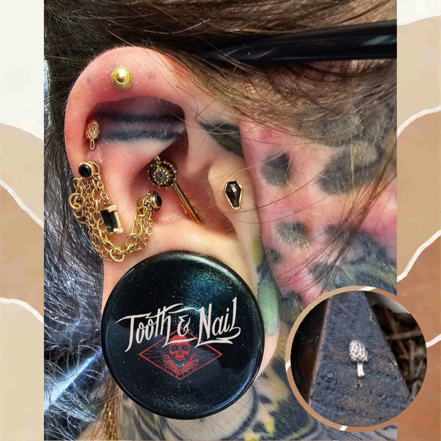 Ear with multiple gold and black piercings, black ear gauge, and neck tattoos