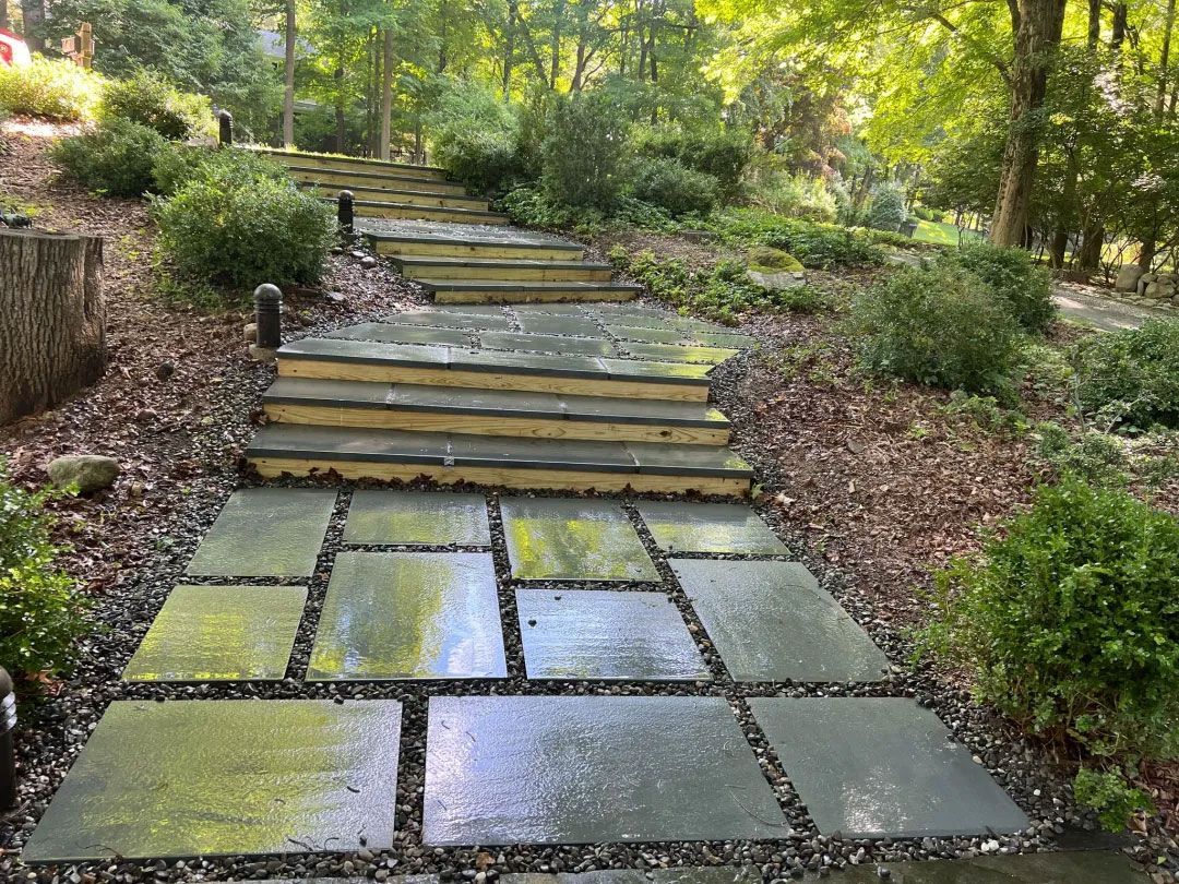 Stone steps and pathway ascending a hillside, surrounded by greenery.