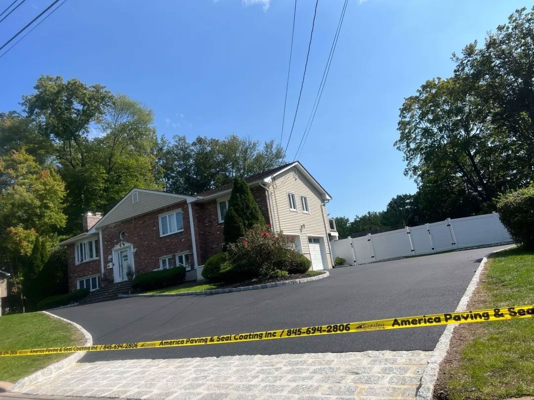 House with paved driveway, power lines overhead, and a white fence on the right. Yellow caution tape in foreground.