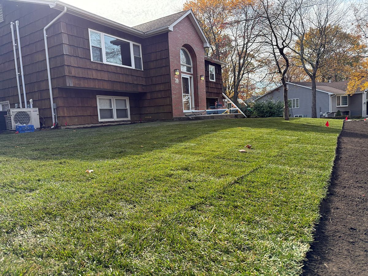 Brown house with green lawn; trees in background.