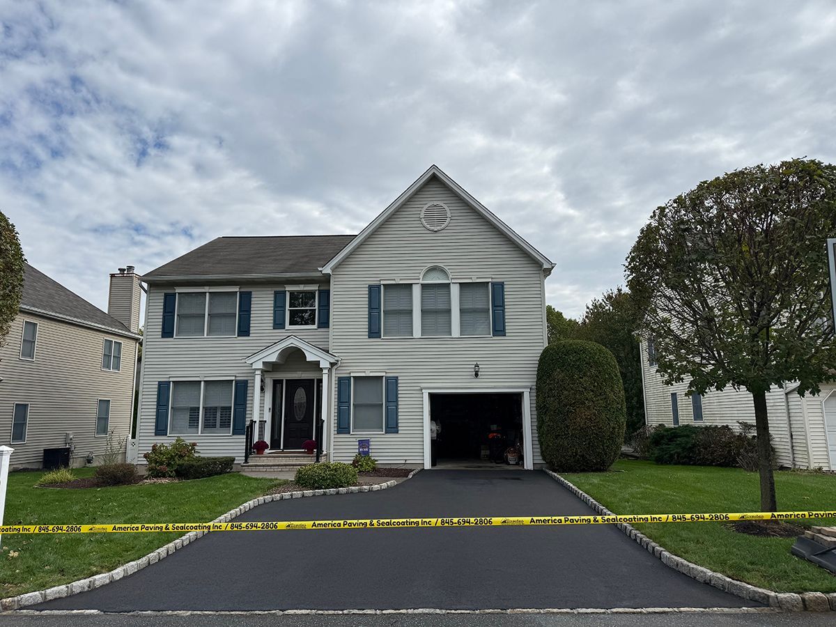 Two-story house with gray siding, blue shutters, and an open garage. Yellow caution tape in foreground. Overcast sky.