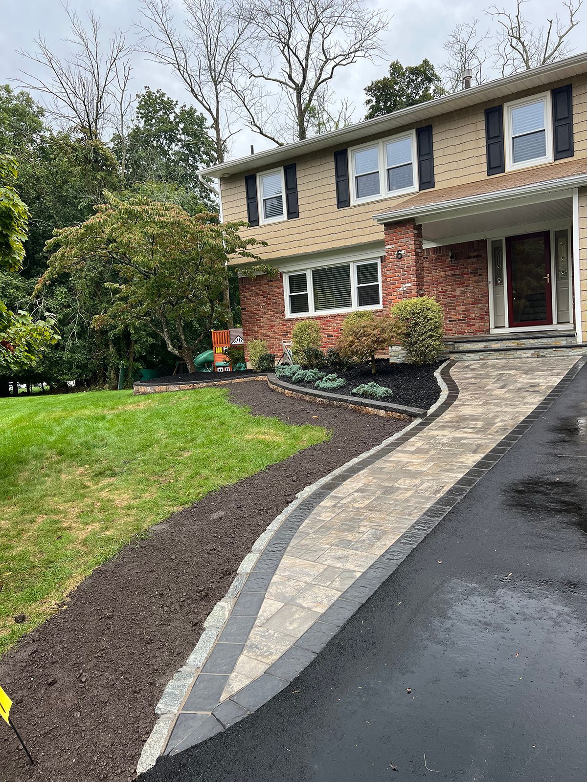 A two-story house with a brick facade and a patterned walkway leading to the front door.
