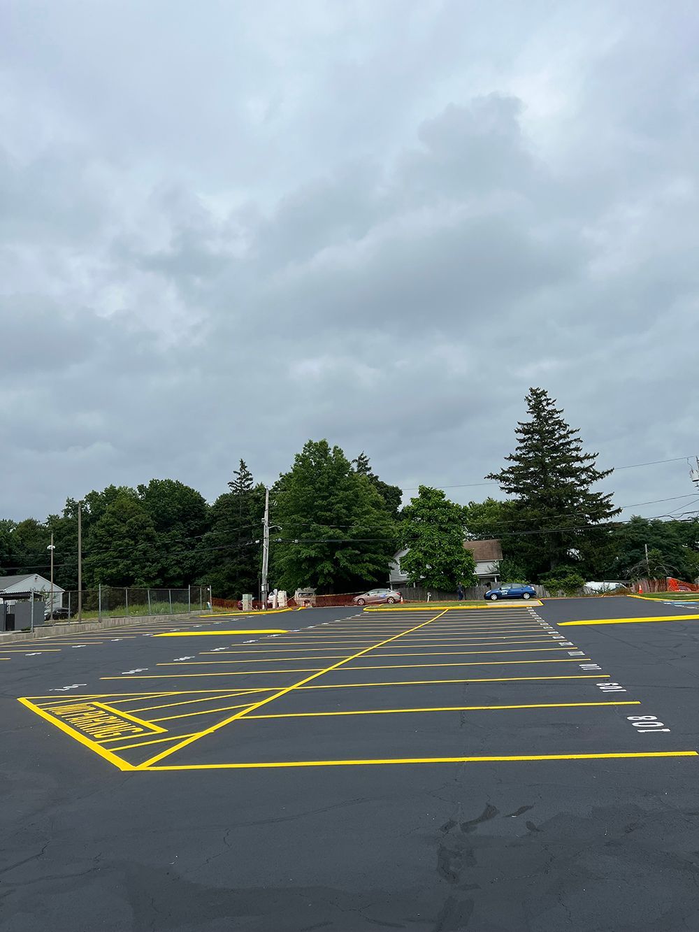 Empty parking lot with yellow lines and markings under cloudy sky.