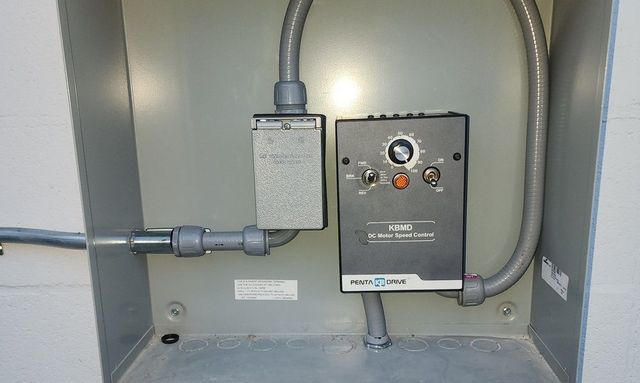 Electrical control panel with conduit and wiring inside a gray utility cabinet.