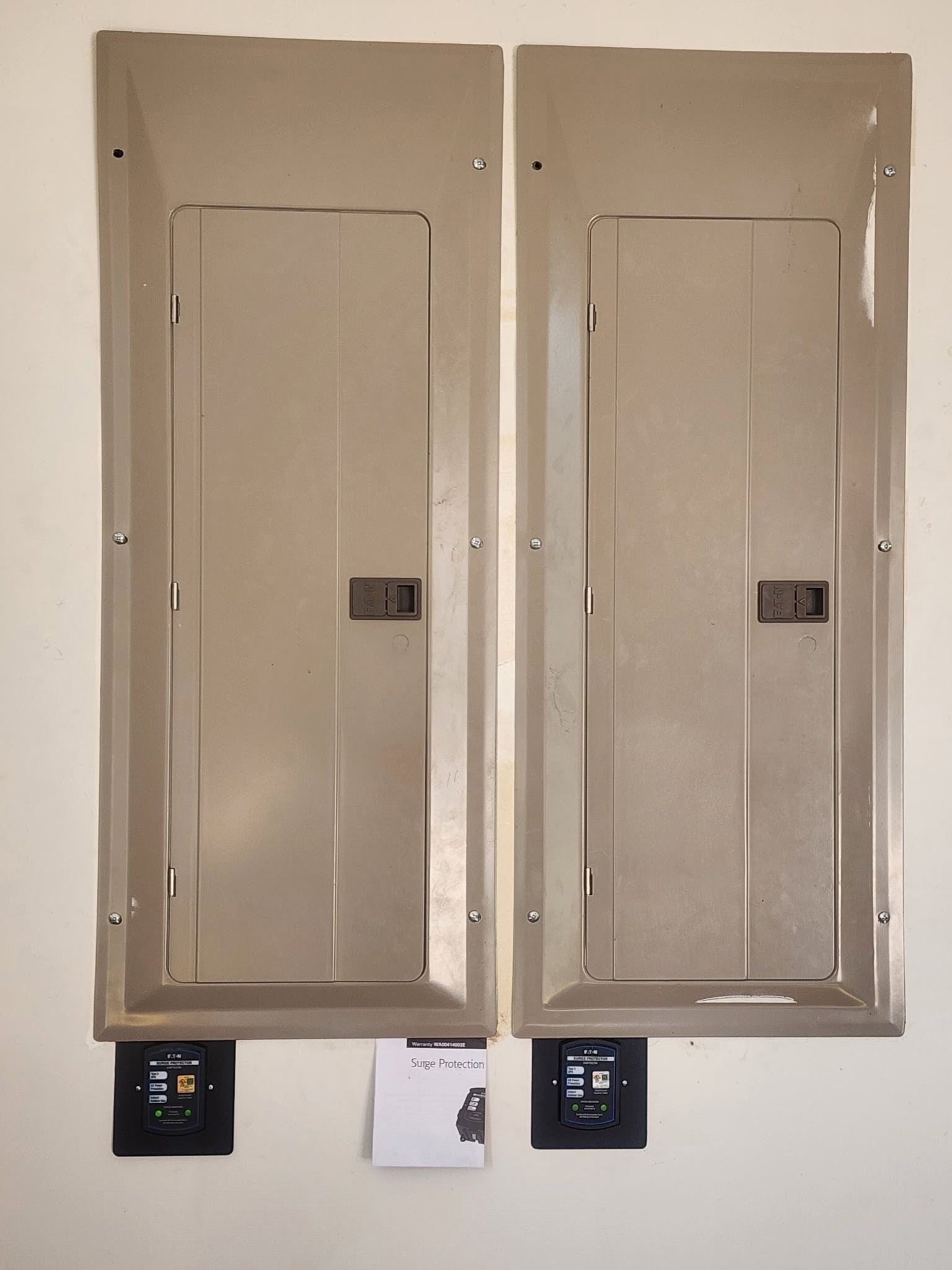 Two beige electrical breaker panels mounted side by side on a wall.