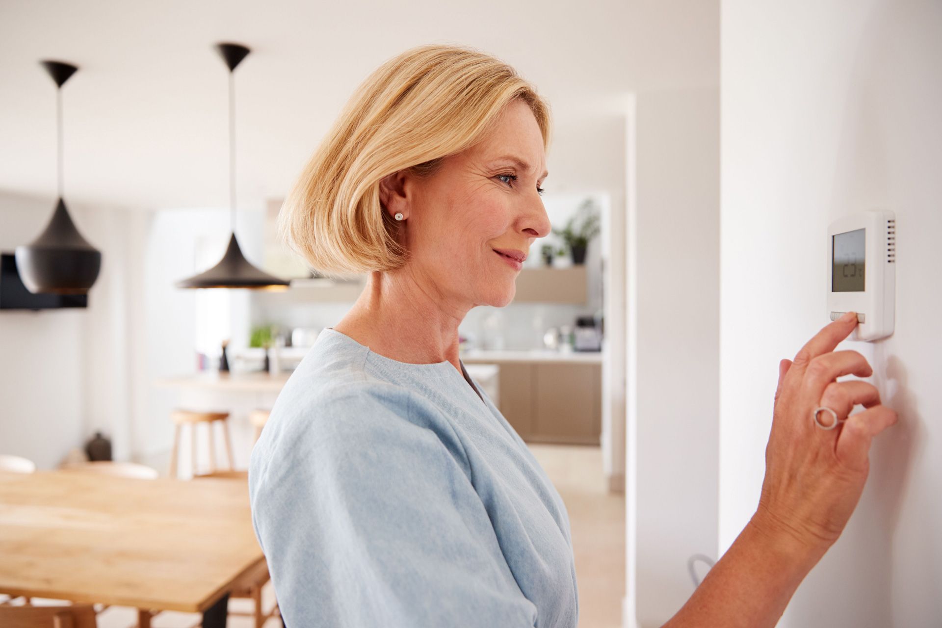 Woman adjusting the thermostat in her home