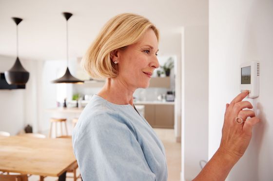 Woman adjusting the thermostat in her home