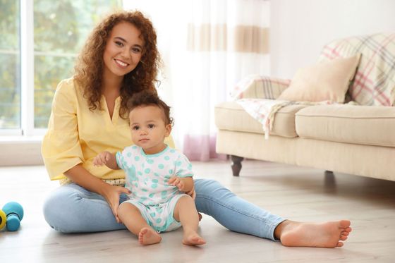 Woman with a baby sitting on the living room floor