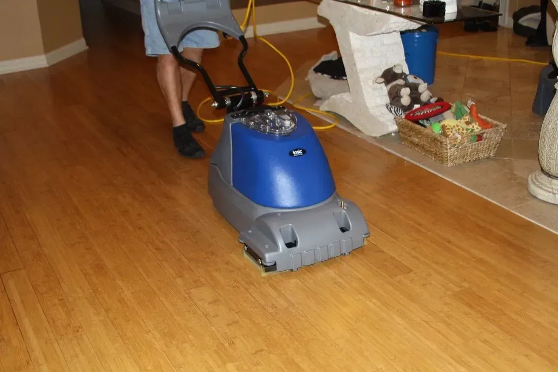 A person is using a machine to clean a wooden floor