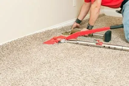 A man is installing a new carpet in a room.