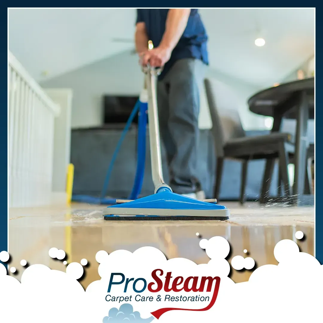 A man is using a vacuum cleaner to clean a hardwood floor.