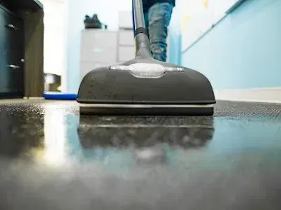 A person is using a vacuum cleaner to clean the floor.