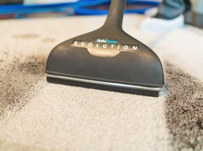 A vacuum cleaner is cleaning a carpet with a brush.