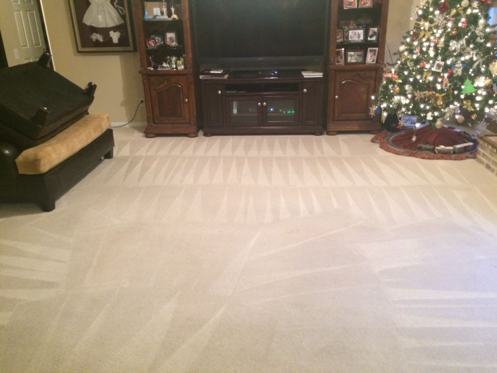 A living room with a christmas tree and a flat screen tv.