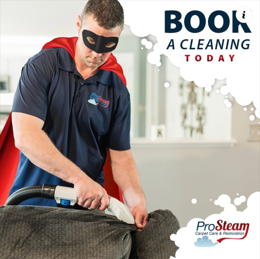 A man in a cape and mask is cleaning a couch