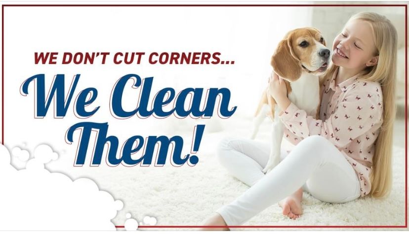 A girl is sitting on the floor holding a dog.