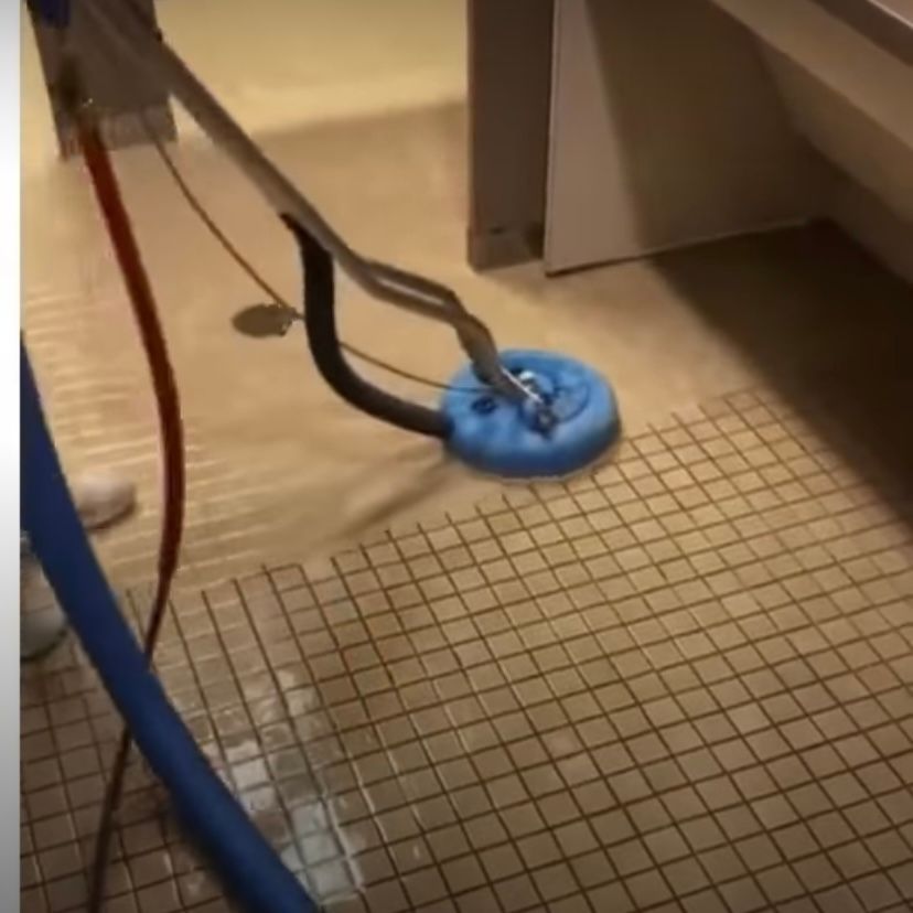 A person is cleaning a tiled floor with a machine