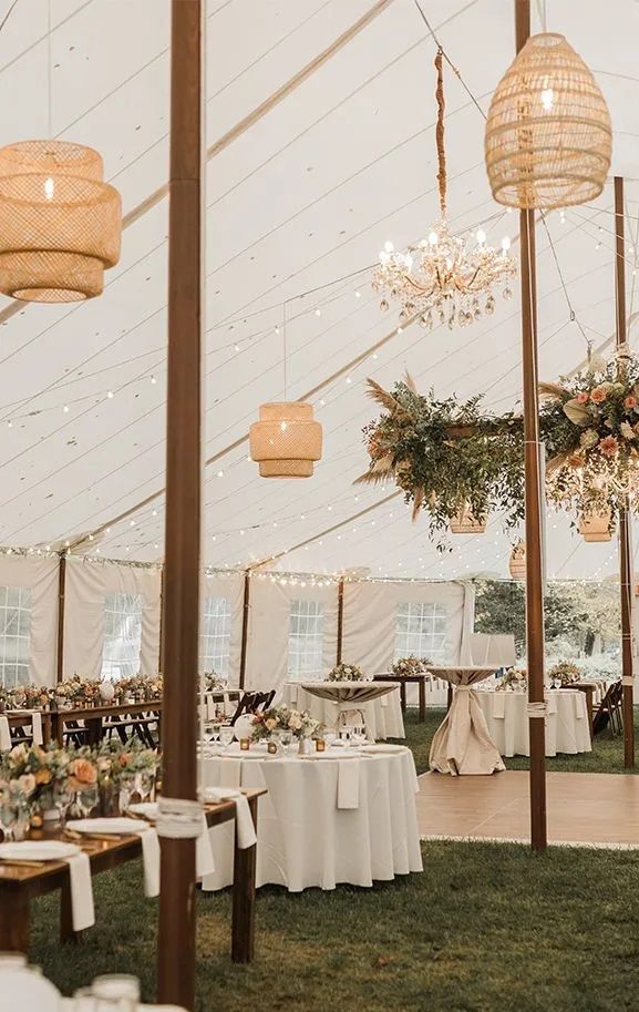 A large tent with tables and chairs set up for a wedding reception.