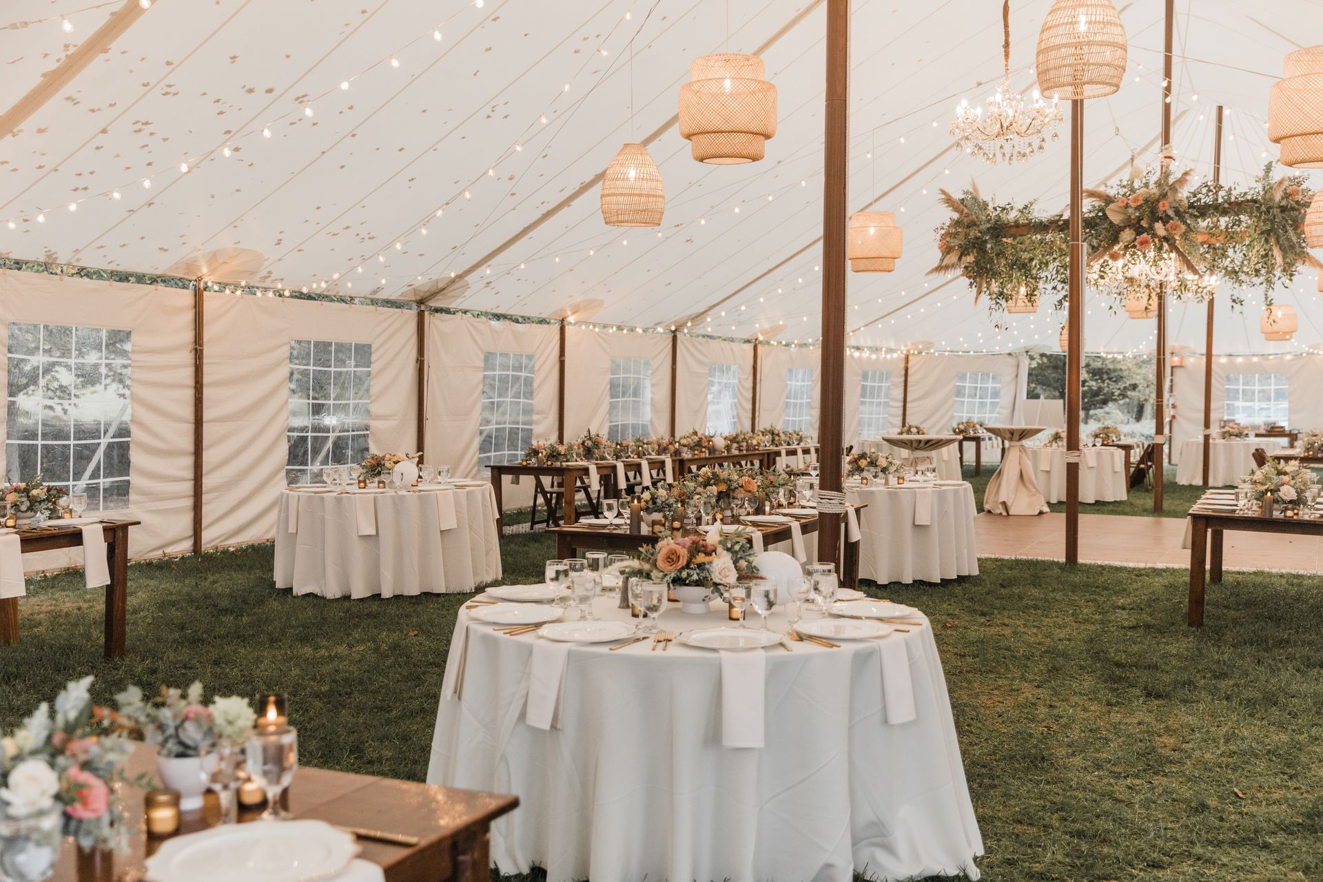 A large tent with tables and chairs set up for a wedding reception.