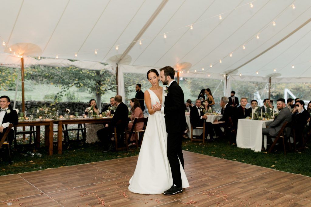 a bride and groom are dancing on a wooden dance floor in a tent