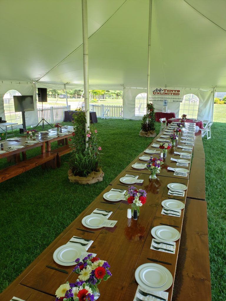 a long table with plates , napkins , and silverware under a tent