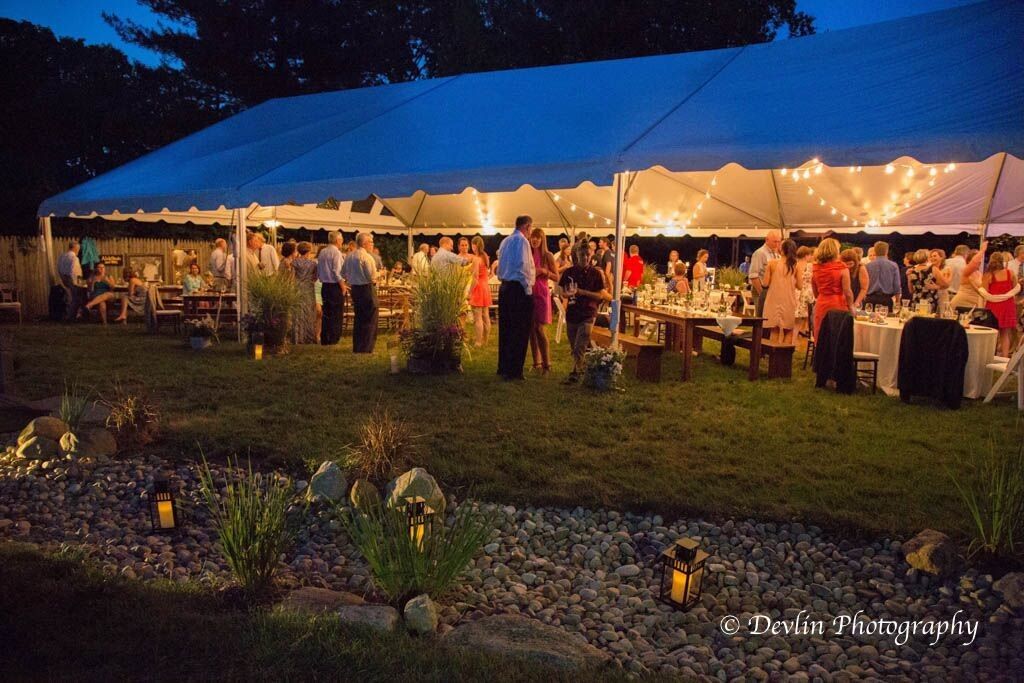 a group of people are standing under a tent at night