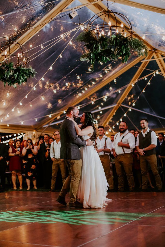 a bride and groom are dancing under a clear tent at their wedding reception
