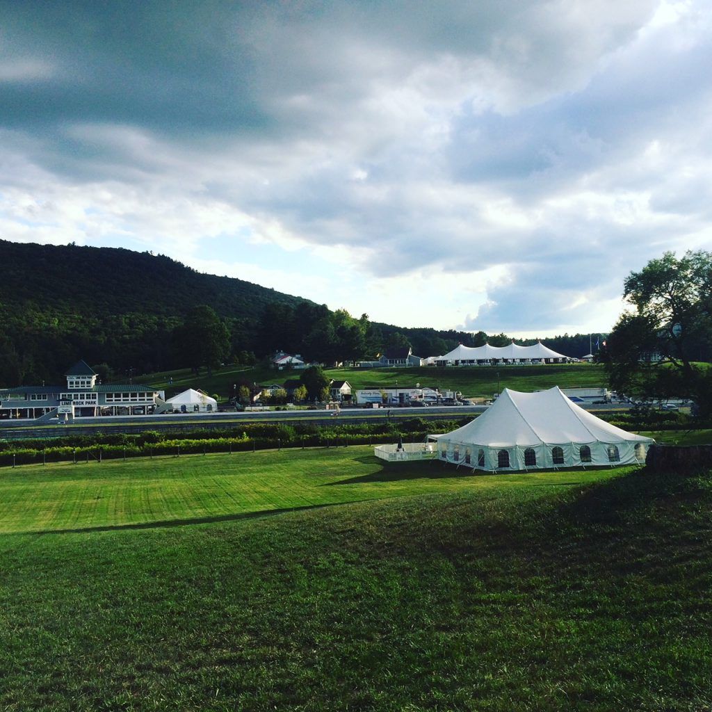 a large white tent sits in the middle of a grassy field
